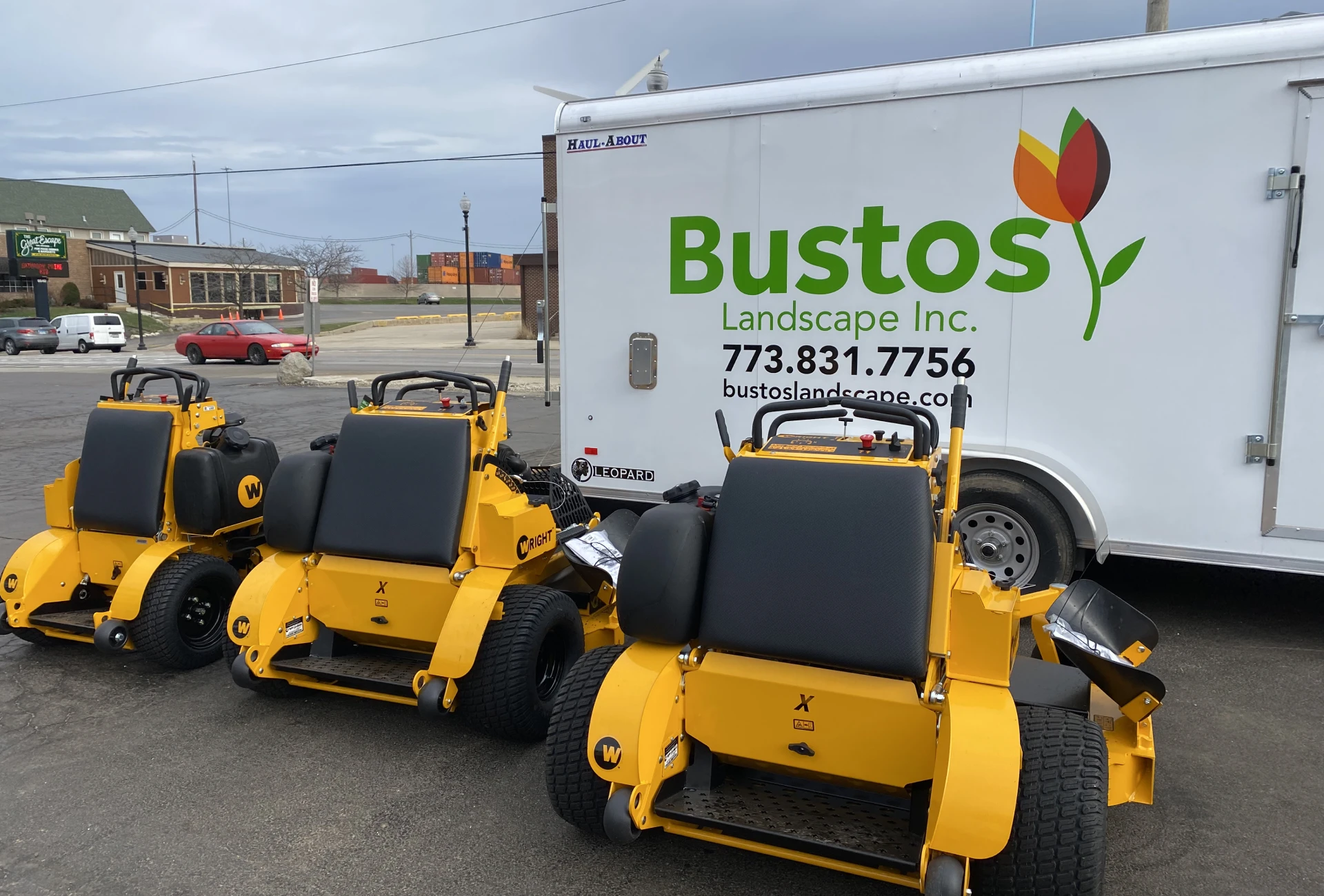 Two yellow lawn mowers parked near a landscaping truck.